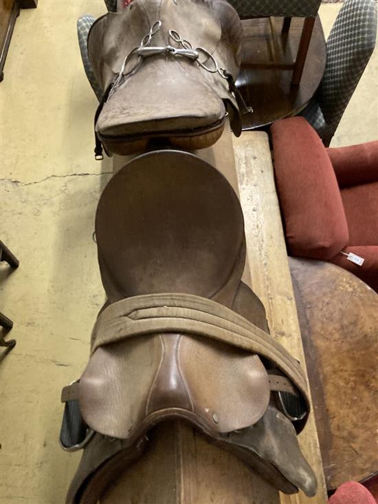 Two tan leather saddles on a pine saddle stand